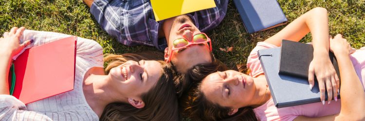 Studenci odpoczywający na trawie po zajęciach, rozmawiający i korzystają z czasu wolnego